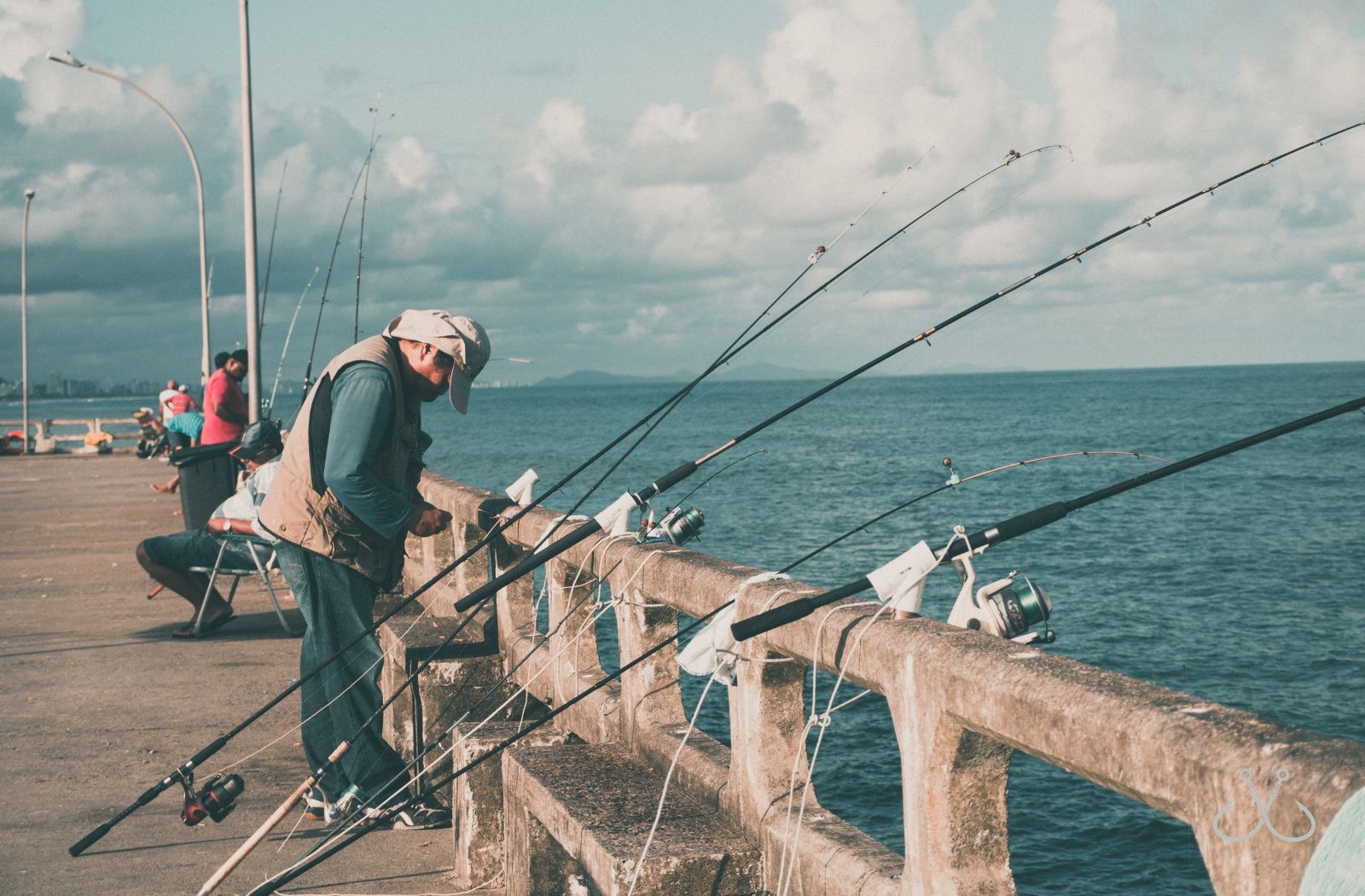 fisherman on a cement fishing pier with fishing poles
