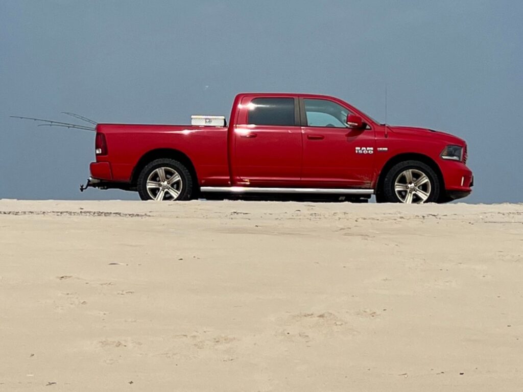 Red 4 wd pickup truck on the beach