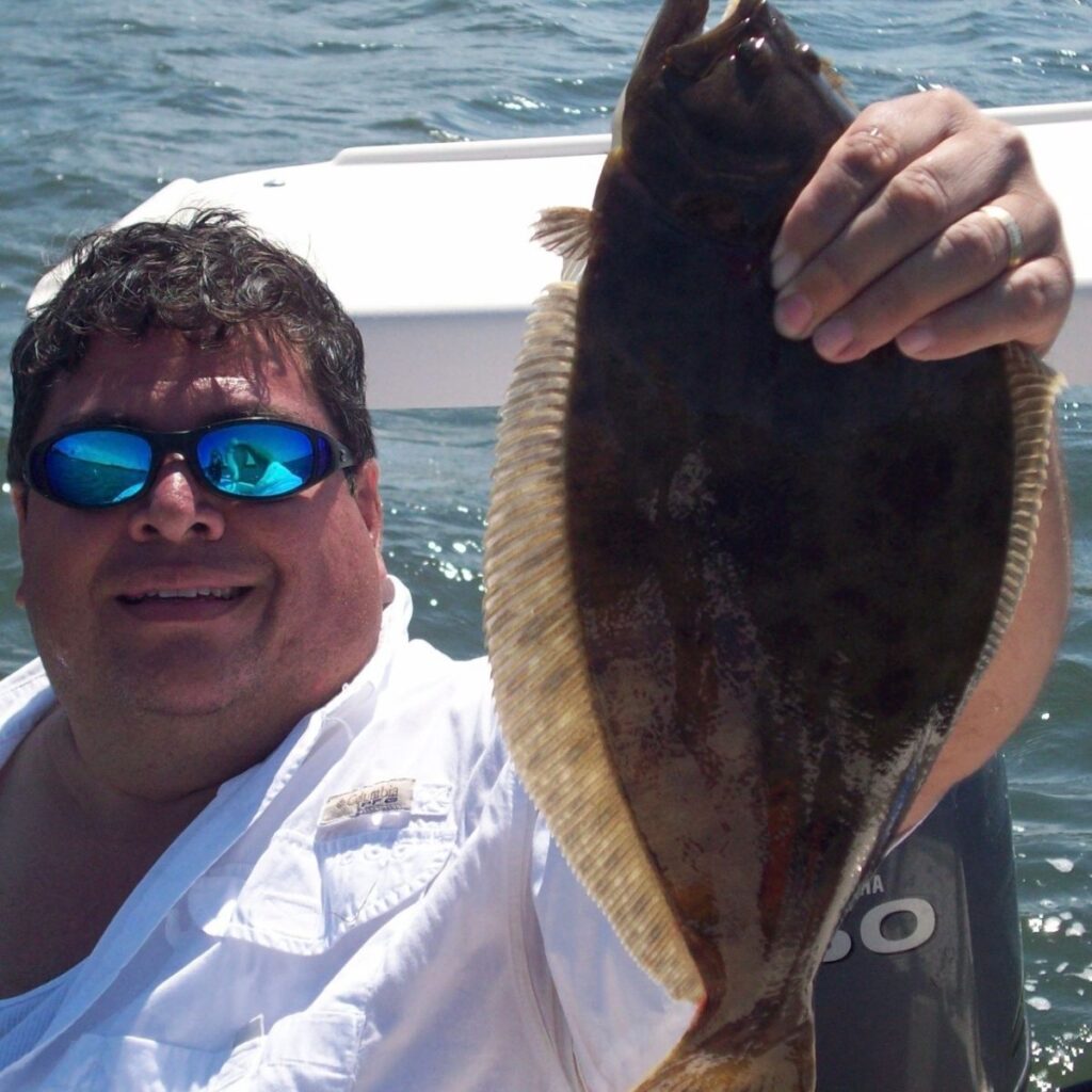Captain Hank holding a fluke caught during a fall fishing trip on Long Island